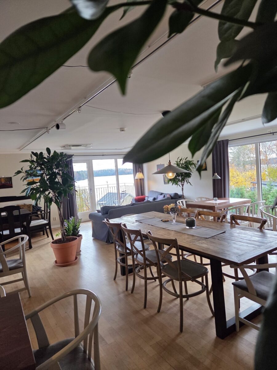 rum med olika bord och växter där  gäster kan sitta och fika och ha utsikt över toftasjön
