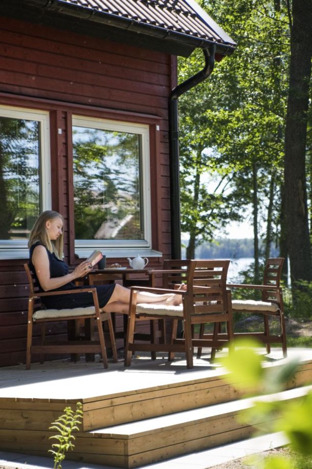 Eine Frau sitzt an einem Sommertag vor dem Hotel Toftastrand und liest.